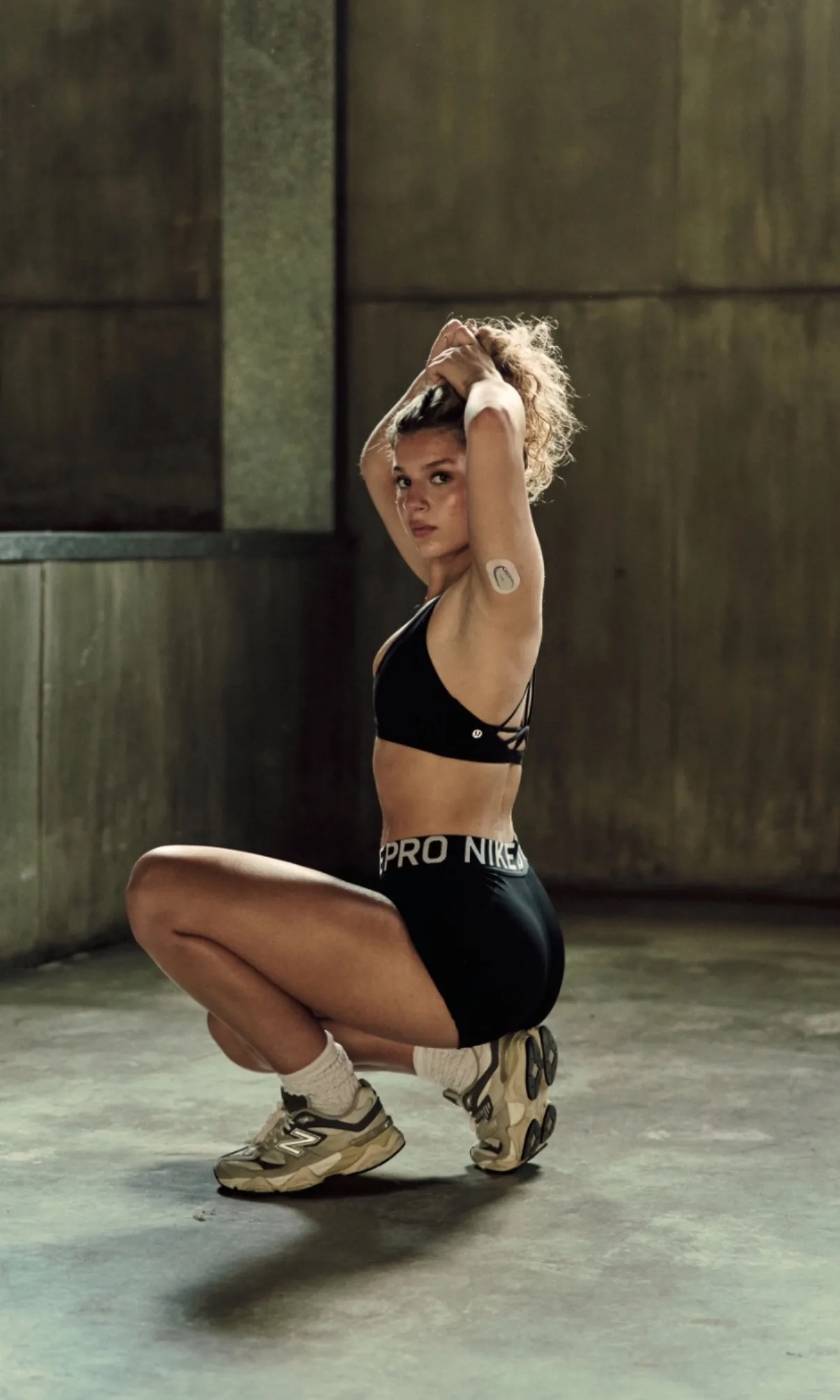Monica, co-founder of Start Strong, crouching in workout gear in an industrial space.